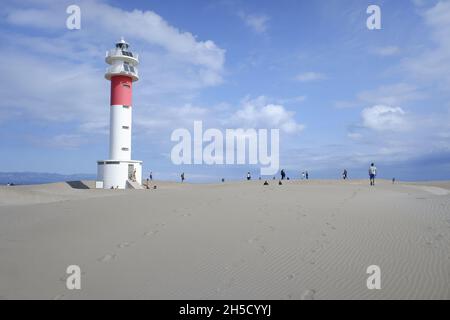 La gente cammina sulla sabbia dura vicino al faro della spiaggia di Fangar nel delta dell'Ebro. Foto Stock