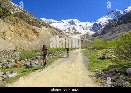 Grigioni, Svizzera - Giugno 2021: Ciclisti in mountain bike sul sentiero escursionistico fino al ghiacciaio di Morteratsch. Il più grande ghiacciaio del Bernina Foto Stock