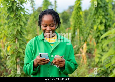 Cheerl agricoltore africano contando denaro sul calcolatore del telefono Foto Stock