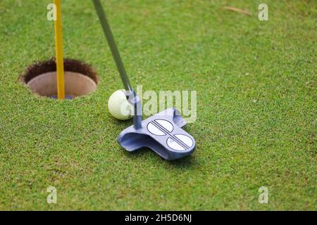 I club di golf e la palla giacciono sull'erba verde in un raggio di sole eterno. Foto di alta qualità Foto Stock