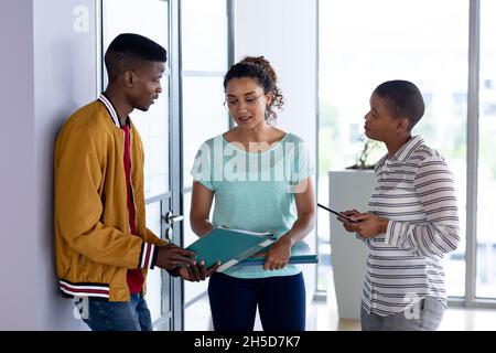 Colleghi maschi e femmine multirazziali in casuals discutere su documento in ufficio creativo Foto Stock