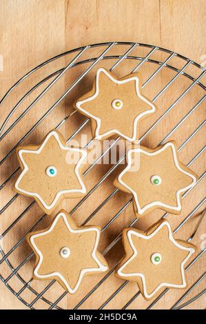Biscotti Star pan di zenzero con glassatura su griglia di raffreddamento, asse di legno Foto Stock