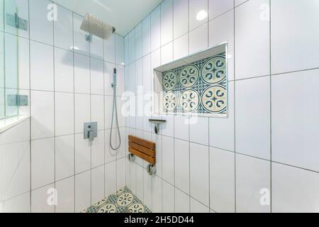 Interno cabina doccia con piastrelle bianche in ceramica e piastrelle in cemento con motivi blu Foto Stock