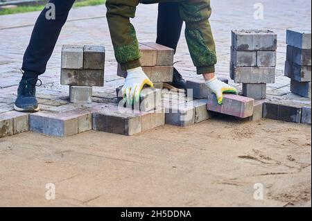 posa di lastre di pavimentazione sulla sabbia con le mani Foto Stock