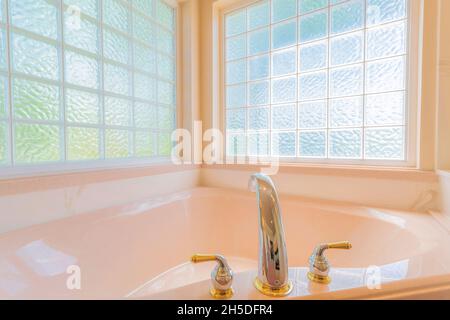 Vasca ad angolo con ponte montato ampiamente in acciaio inox con rubinetto d'oro Foto Stock