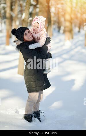 Ritratto di felice mamma sorridente con bambino sullo sfondo del parco invernale Foto Stock