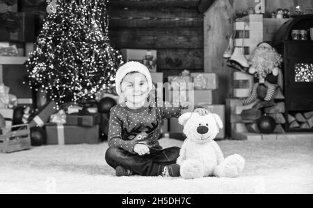 Bambino carino. Piccolo ragazzo giocare vicino albero di natale. Divertimento per bambini a casa. Buon natale a tutti. Natale presente. Vacanze invernali. Il bambino felice festeggia l'anno nuovo Foto Stock