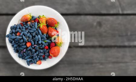 succulca di miele e fragole su un piatto su una base di legno sfocato Foto Stock