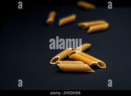 Primo piano di pasta penne non cotta su una superficie scura Foto Stock