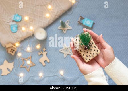 Un piccolo regalo di Natale nelle palme da donna, sullo sfondo di una maglia blu Foto Stock