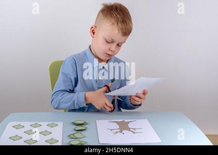 Il figlio taglia le foglie per creare un albero di famiglia. Foto di alta qualità Foto Stock