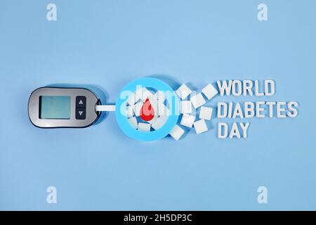 Concetto di giornata mondiale del diabete. Caduta di sangue rosso in circolo con striscia reattiva per la glicemia e glucometro. Vista dall'alto Foto Stock