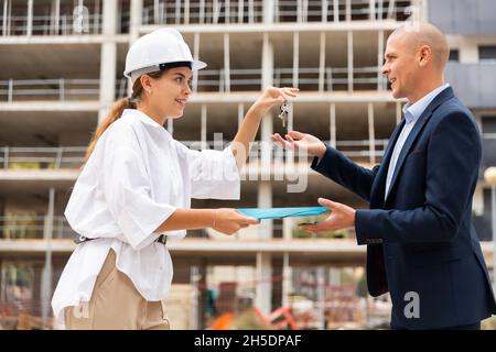 Builder che dà le chiavi al cliente dopo la conclusione del contratto di firma Foto Stock