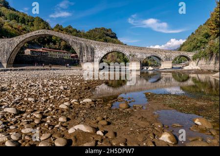 Il letto del fiume Serchio appare quasi asciutto sotto l'antico ponte romano della Maddalena o del Diavolo, Borgo a Mozzano, Italia Foto Stock