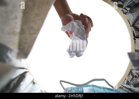 La persona getta un pezzo di carta sbriciolato in Cestino.Visualizza dall'interno cestino Foto Stock