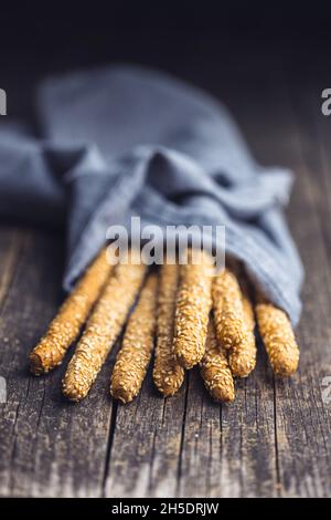 Grissini di grissini. Bastoncini di pane con semi di sesamo su tavola di legno. Foto Stock