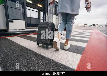 Donna con biglietto d'imbarco che si avvicina al bus navetta dell'aeroporto Foto Stock