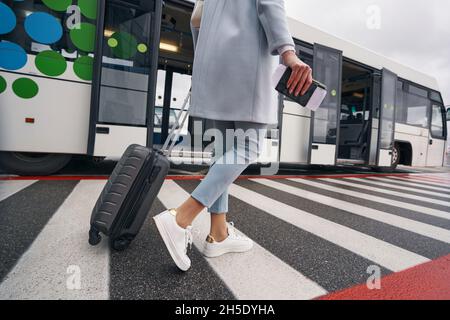 Donna con bagaglio e documento di viaggio che si avvicina bus navetta aeroporto Foto Stock