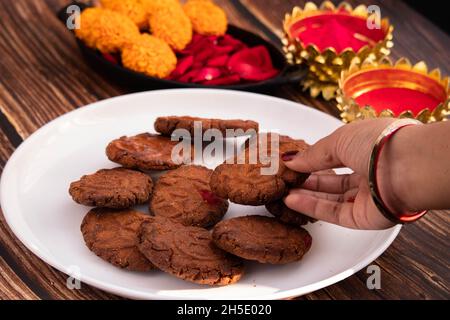 Hands of Girl Holding Indian Mithai Thekua Thokwa o Thekuwa è fatto di grano e Meetha frutta secca è offerto a Dio Sole durante Auspicious Chhath PUJ Foto Stock