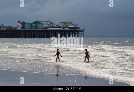 Brighton UK 19 novembre 2021 - nuotatori godersi la bassa marea sulla spiaggia di Brighton in una mattinata sovrastante lungo la costa meridionale con l'occasionale esplosione di sole attraverso le nuvole scure : Credit Simon Dack / Alamy Live News Foto Stock