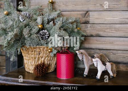 Un cavallo souvenir, una lattina di lamponi contro uno sfondo di rami di abete in un cestino di vimini. Decorazioni di Natale Foto Stock