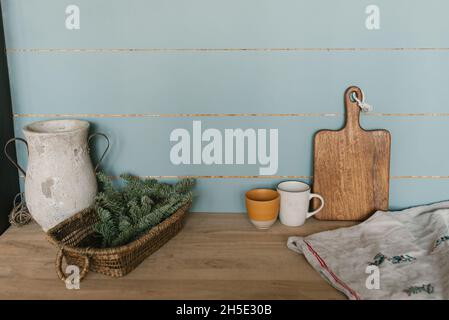 Primo piano dell'interno della cucina. Decorazione di Natale. Rami di abete in un cestino di vimini. Muro in legno di menta, ripiani in legno con utensili da cucina. VIN Foto Stock