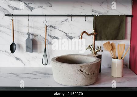 Lavabo in pietra con miscelatore vintage su sfondo di cucina in marmo Foto Stock