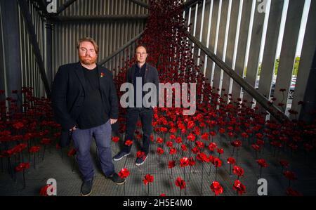 L'artista Paul Cummins (a sinistra) e il designer Tom Piper si trovano accanto a "Poppies: Wave and Weeping Window", una nuova opera d'arte che comprende migliaia di papaveri in ceramica fatti a mano che scendono a cascata per 30 metri e si riunono all'interno dell'Air Shard a IWM North a Manchester. Le sculture di papavero erano originariamente parte di 'Blood Swept Lands and Seas of Red' presso la Torre di Londra nel 2014, e più tardi 'Poppies: Wave and Weeping Window' che fece un giro nel Regno Unito tra il 2014 e il 2018. Data foto: Martedì 9 novembre 2021. Foto Stock