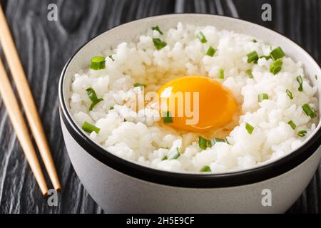 Tamago kake gohan riso riempito con uovo è un piatto semplice ma incredibilmente popolare in cucina giapponese primo piano nella ciotola sul tavolo. Orizzontale Foto Stock