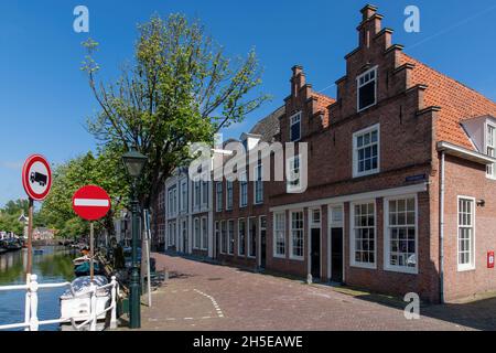 Alkmaar, Paesi Bassi-giugno 2021: Vista delle case dei canali tradizionali con scuderie sul canale Oudegracht fiancheggiato da alberi; Foto Stock