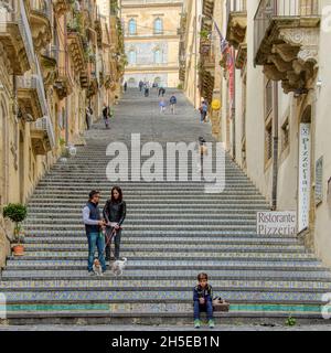 Caltagirone , Sicilia, Italia - 10 ottobre 2015: Un ragazzino siede in fondo alla Scalinata di Santa Maria del Monte, famosa in tutto il mondo Foto Stock