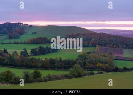 Splendido paesaggio di alba che si affaccia sul villaggio di Oare dal bordo sud del Marlborough Downs, adiacente a Pewsey vale, Wiltshire AON Foto Stock