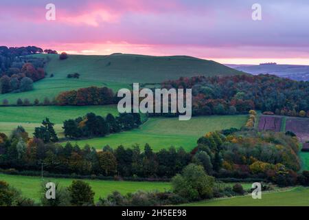 Splendido paesaggio di alba che si affaccia sul villaggio di Oare dal bordo sud del Marlborough Downs, adiacente a Pewsey vale, Wiltshire AON Foto Stock