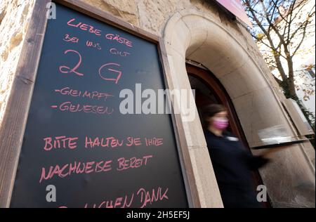 Stoccarda, Germania. 9 novembre 2021. Di fronte ad un ristorante nella parte ovest di Stoccarda è appeso un cartello con l'iscrizione "Egregi ospiti con noi applica 2G - vaccinati - recuperati si prega di avere la prova pronta". Qualora il cosiddetto livello di allerta dovesse entrare in vigore nel Baden-Württemberg, l'ordinanza di Corona prevede la regola del 2G in tutto lo Stato, ad esempio nei ristoranti, nei musei, nelle mostre e nella maggior parte degli altri eventi pubblici. Credit: Marijan Murat/dpa/Alamy Live News Foto Stock