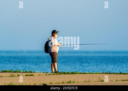 Un uomo soleggiato che pesca lungo il molo all'alba in un parco locale vicino a Egg Harbor nella contea di Door Wisconsin. Foto Stock