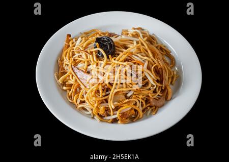 Tagliatelle asiatiche Chow Mein con pollo, verdure e funghi, in un piatto bianco. Un popolare piatto orientale. Su sfondo nero. Foto Stock