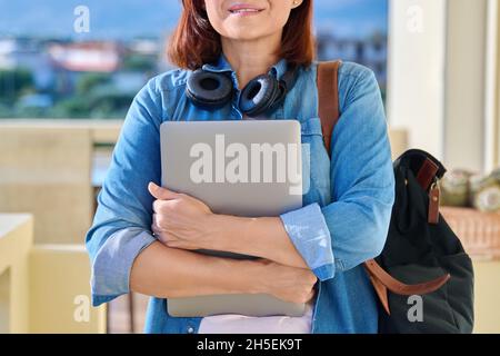 Ritratto di una donna in cuffie wireless con un computer portatile e uno zaino Foto Stock