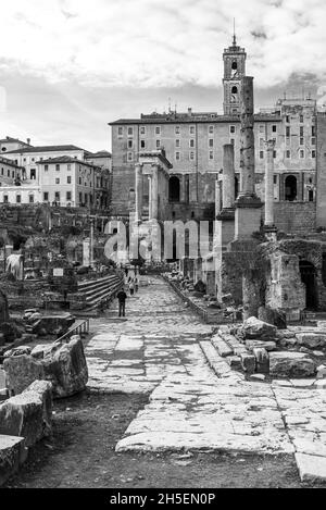 Foto in bianco e nero del paesaggio italiano che mostra le rovine del foro romano di fronte ad una chiesa medievale Foto Stock