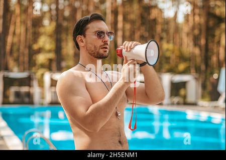 Bagnino maschio che avverte i visitatori della situazione di emergenza Foto Stock