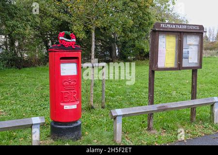 Felpham Village Post Box filato bombardato con corona di papavero uncinetto recante la scritta 'Lest We Forget' Foto Stock