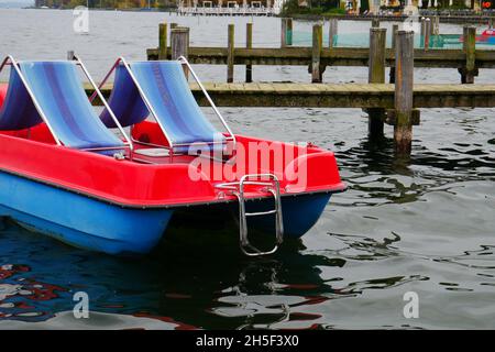 pedalò di plastica rosso-blu con lettini sul ponte si trova su una passerella sul lago starnberg vicino a monaco Foto Stock