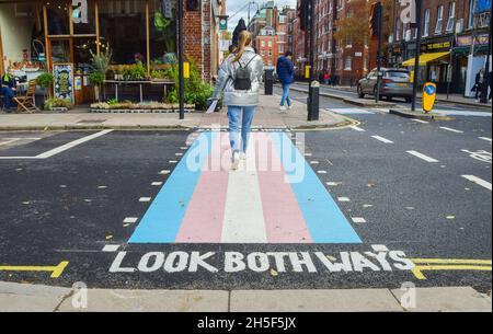 Londra, Regno Unito. 9 novembre 2021. Una donna cammina lungo un attraversamento pedonale con i colori della bandiera trans a Bloomsbury.quattro nuovi incroci con colori della bandiera trans sono stati svelati su Marchmont Street e Tavistock Place, a sostegno della comunità trans. (Foto di Vuk Valcic/SOPA Images/Sipa USA) Credit: Sipa USA/Alamy Live News Foto Stock