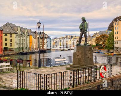 La statua del ragazzo pescatore o Fiskergutten sul lungomare del porto interno di Alesund. Foto Stock