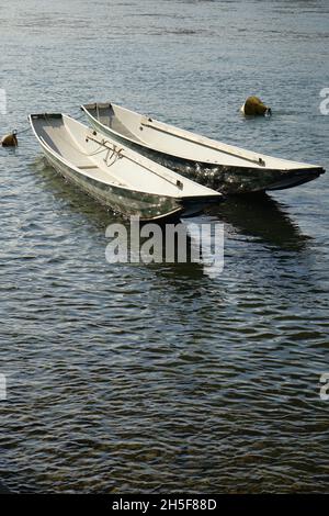 Piccole imbarcazioni da pesca tradizionali con riflessi soleggiati sul fiume Reno a Kleinbasel, Basilea, Svizzera Foto Stock