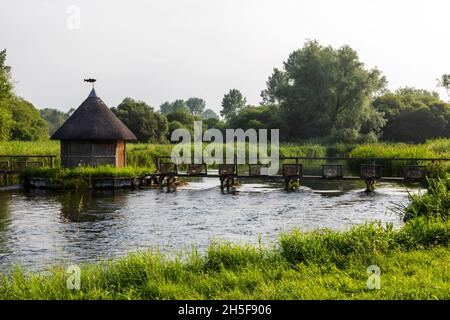 Inghilterra, Hampshire, Test Valley, Stockbridge, Longstock, Leckford Estate, River Test e tradizionale capanna dei pescatori con tetto in paglia Foto Stock