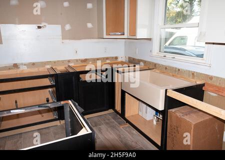Una casa residenziale che passa attraverso una cucina rimodellata con armadi e banchi che sono istallati e un lavandino. Foto Stock