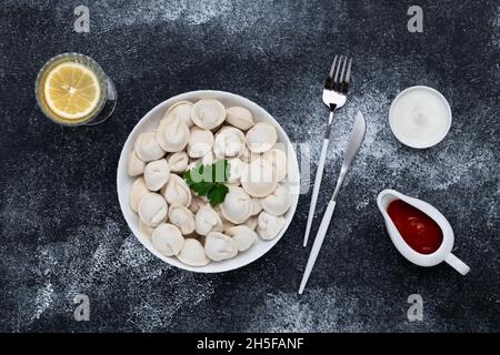 Una ciotola di gnocchi sul tavolo nero. Vista dall'alto. Sfondo di cibo scuro. Il Pelmeni è un piatto di cucina tradizionale russa Foto Stock