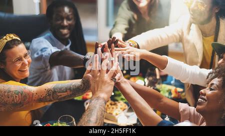 Gruppo diversificato di persone che si uniscono a mani seduti al tavolo da pranzo primo piano - gruppo multietnico di amici che si divertono a cooperare insieme - concetto di succhia Foto Stock