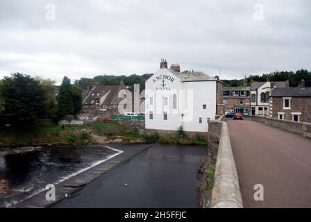 River South Tyne scorre sotto l'Old Haydon Bridge con l'Anchor Hotel dipinto di bianco a Haydon Bridge, Northumberland, Inghilterra, Regno Unito Foto Stock