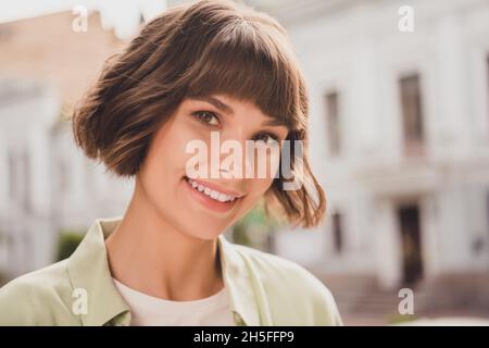 Foto di adorabile giovane donna lucido indossare camicia verde sorridente camminare fuori strada della città Foto Stock